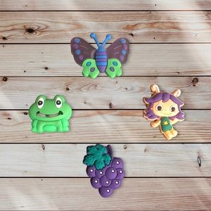 Croc Charms (4):
* Purple 🍇
* Purple/Green 🦋
* Green 🐸 
* Purple Character 💜